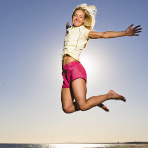 Happy young woman jumping on beach
